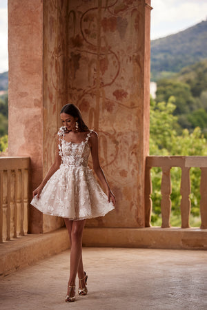 Kurzes Brautkleid Amanda in Skater-Silhouette, ganze Figur mit Blütengirlande an der Schulter