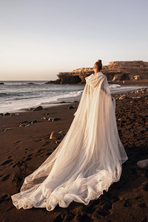Brautkleid Amira von hinten mit langer Schleppe und Cape auf dem Sand