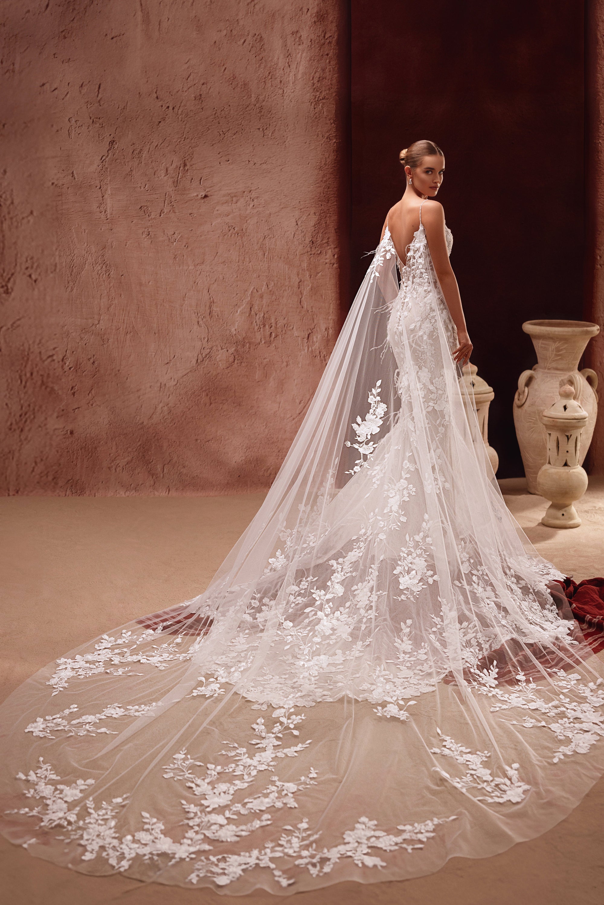Aspasia bridal cape with 3D floral appliqués, crafted from soft tulle, adds a dramatic and romantic touch to the wedding dress.
