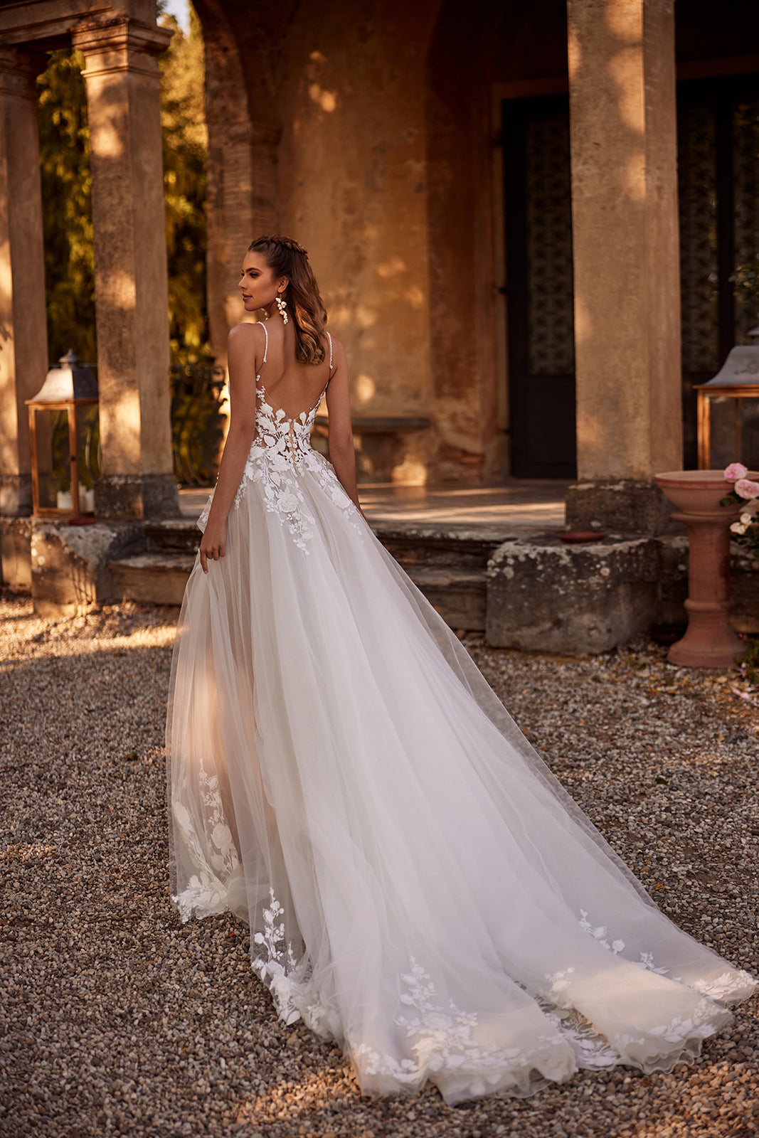 Brautkleid Claire von hinten im Innenhof, offener Rücken und Tüllschleppe mit Blütenspitze