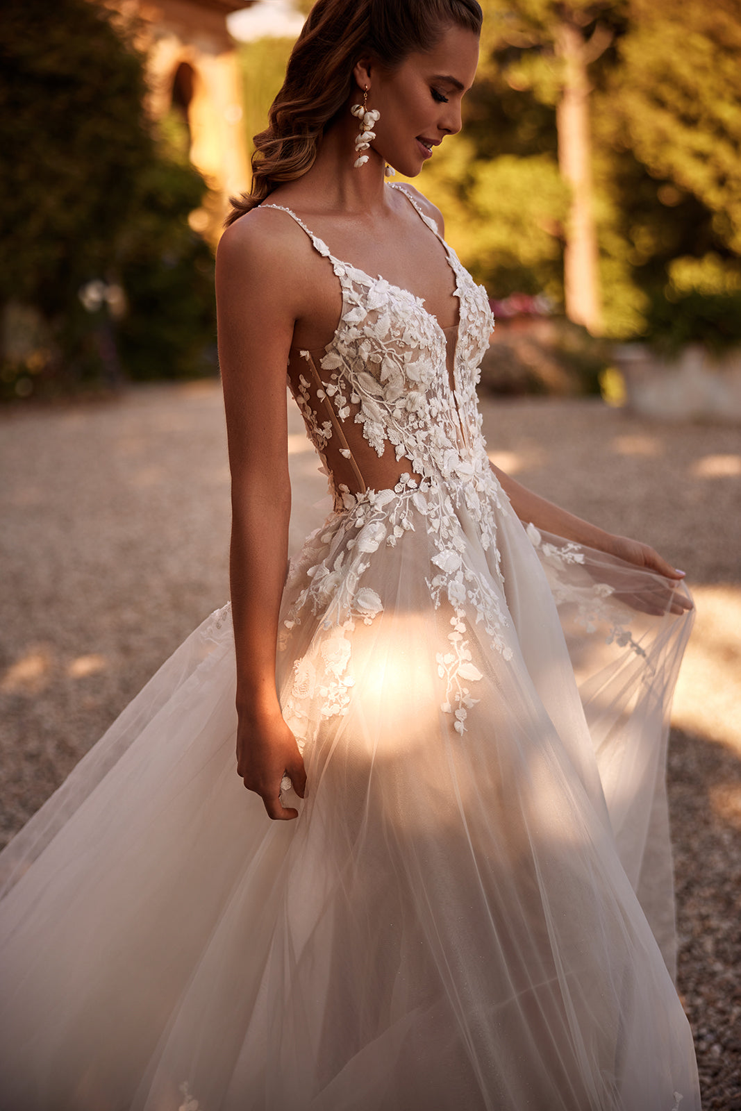 Brautkleid Claire im Profil, Braut rafft den Tüllrock, Mieder mit transparenten Seiten