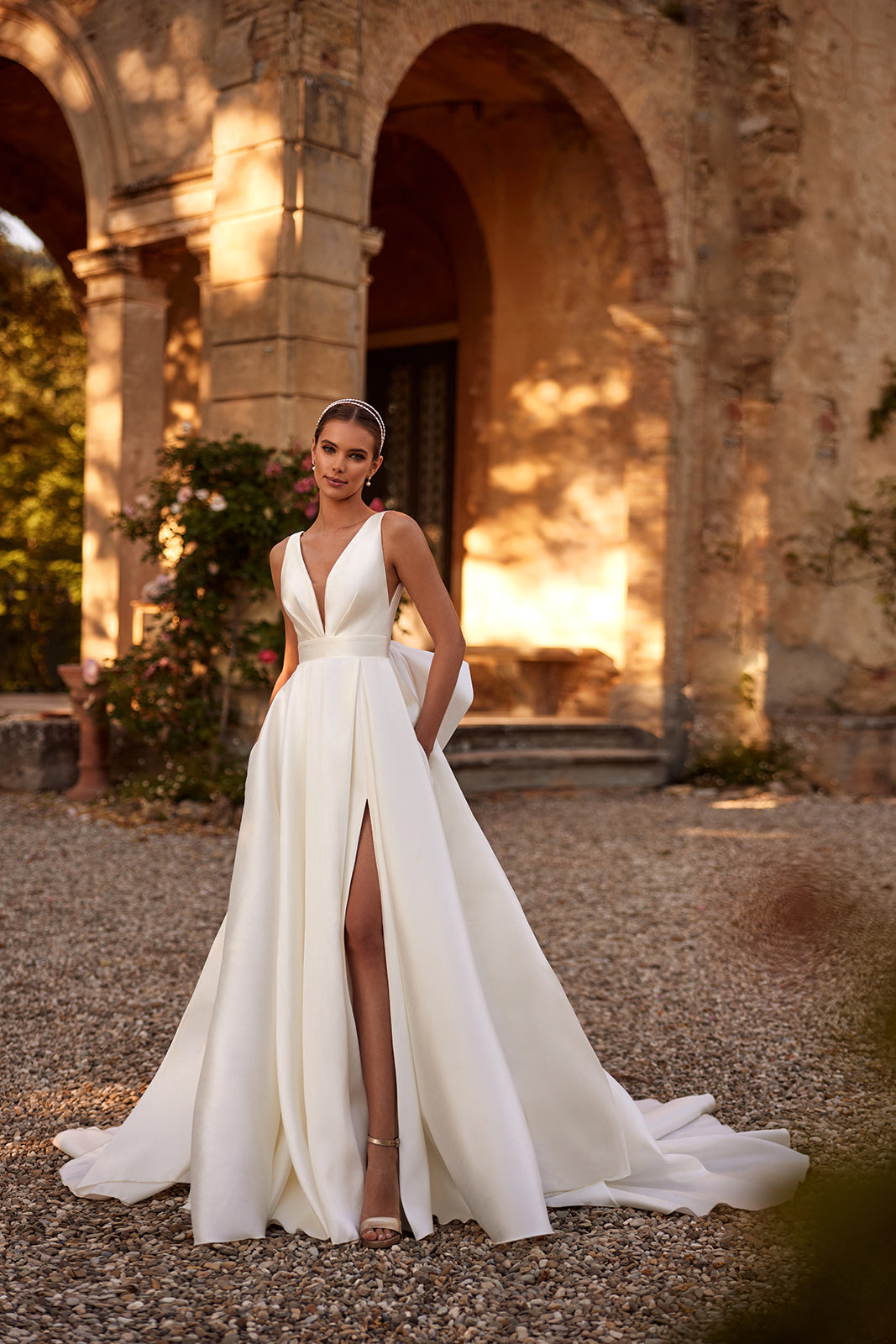Brautkleid Margo in ganzer Figur vor den Arkaden der Villa, Schlitz bis zum Oberschenkel