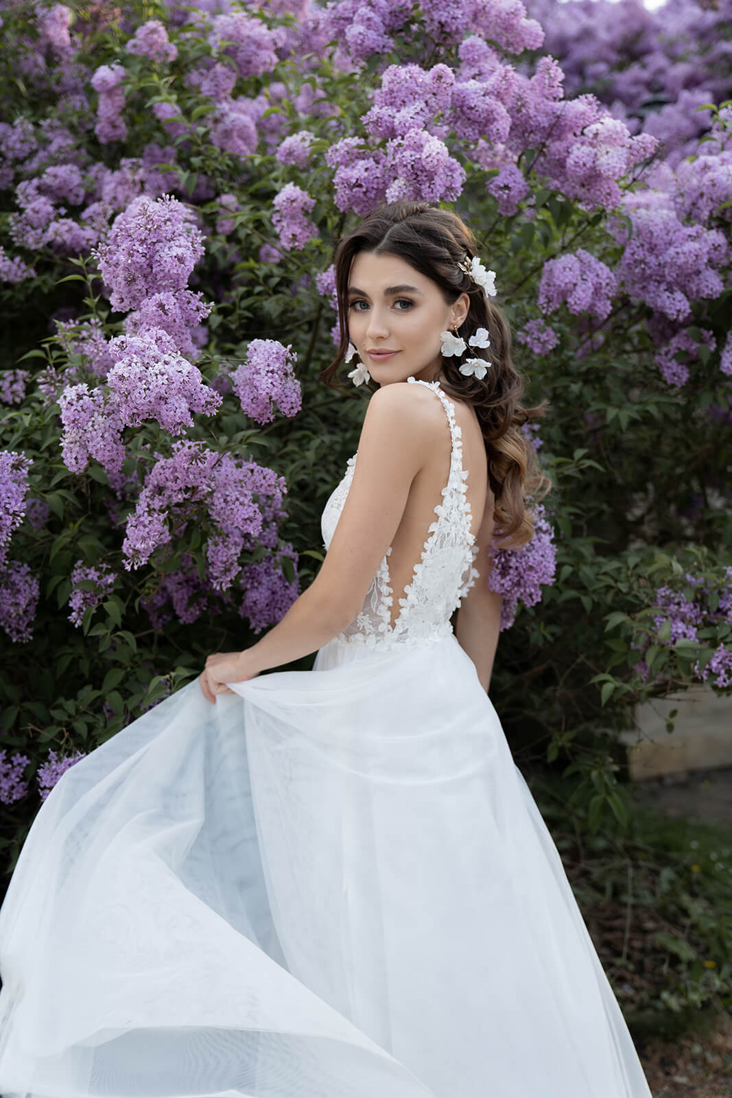 Brautkleid Rosaline von hinten, Braut rafft den Tüllrock, offener Rücken sichtbar