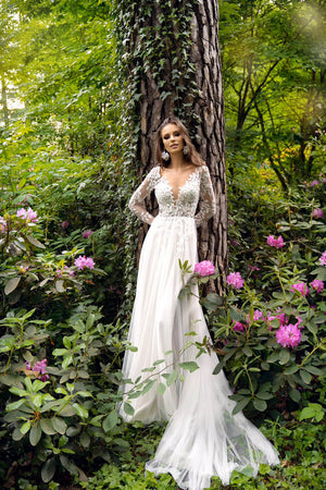 Brautkleid Calista in ganzer Silhouette von vorn, A-Linie aus Tüll vor einem Baumstamm