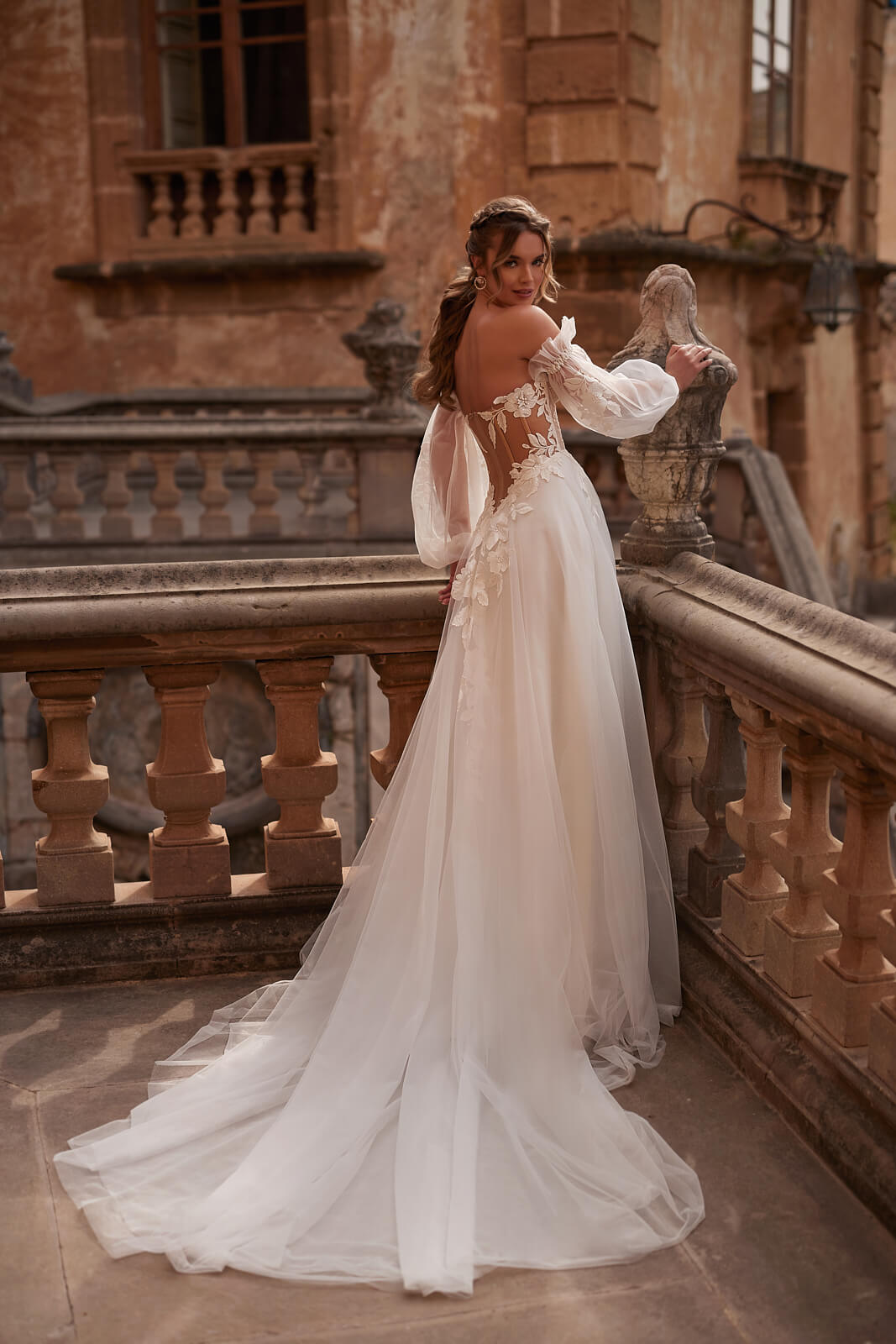 Brautkleid Hermiona von hinten in ganzer Figur, ausgebreitete Tüllschleppe auf der Treppe