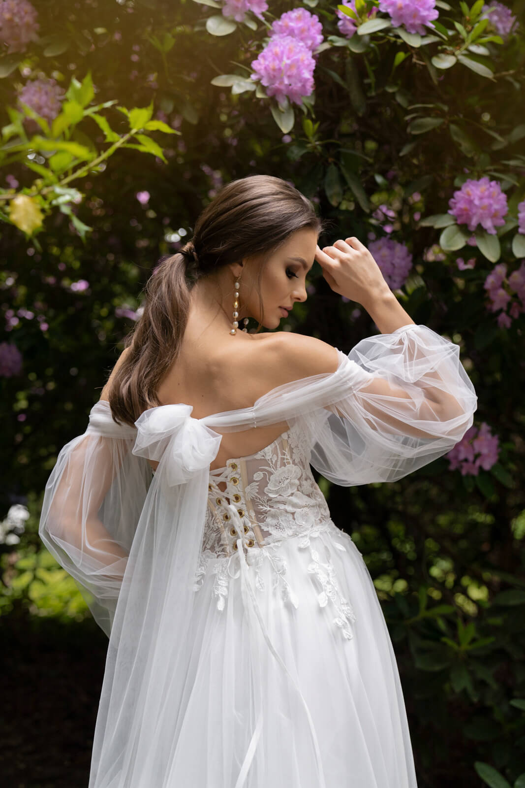 Brautkleid Lanka von der Seite, Braut mit erhobenen Armen, Tüllärmel und Rückenschnürung