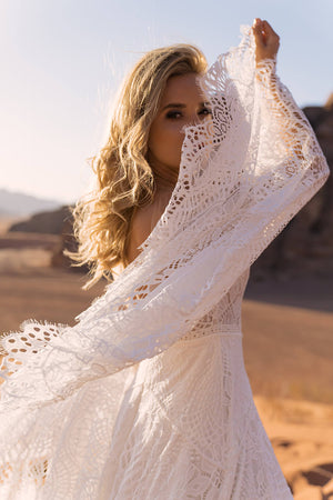 Brautkleid Lea, Detail des weiten Spitzenärmels vor dem Gesicht, Aufnahme in der Wüste