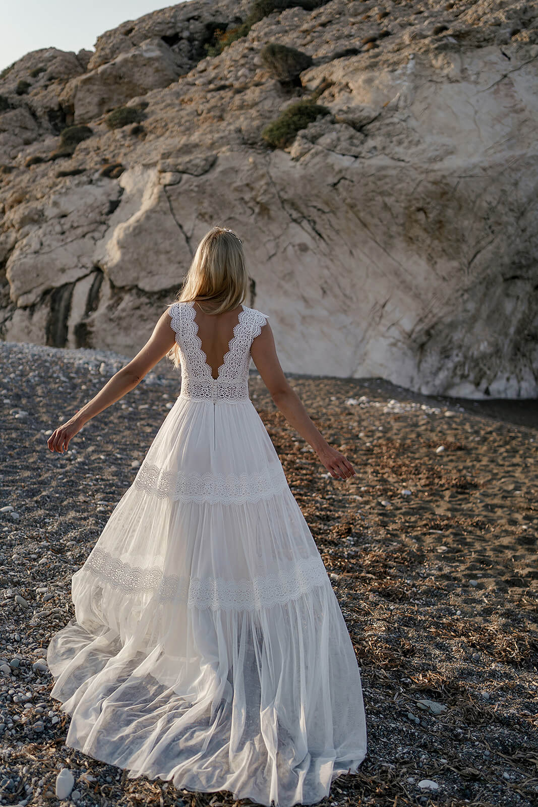Brautkleid Lidia in Bewegung am Kiesstrand, der leichte Rock schwingt zur Seite