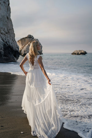 Brautkleid Lidia von hinten am Strand, der Rock wird zur Seite gehalten