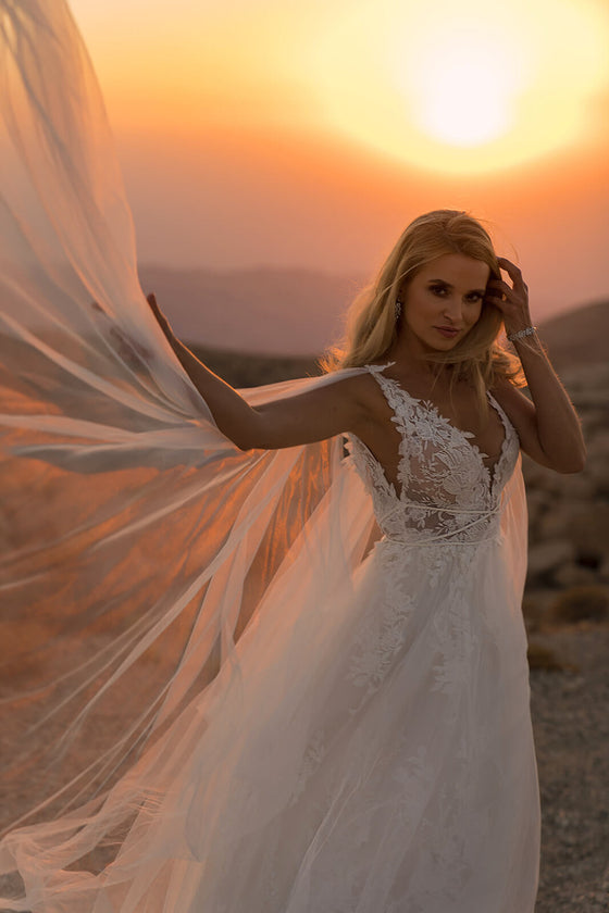 Brautkleid Linda im Sonnenuntergang, Tüllcape weht seitlich vom Schulterträger weg
