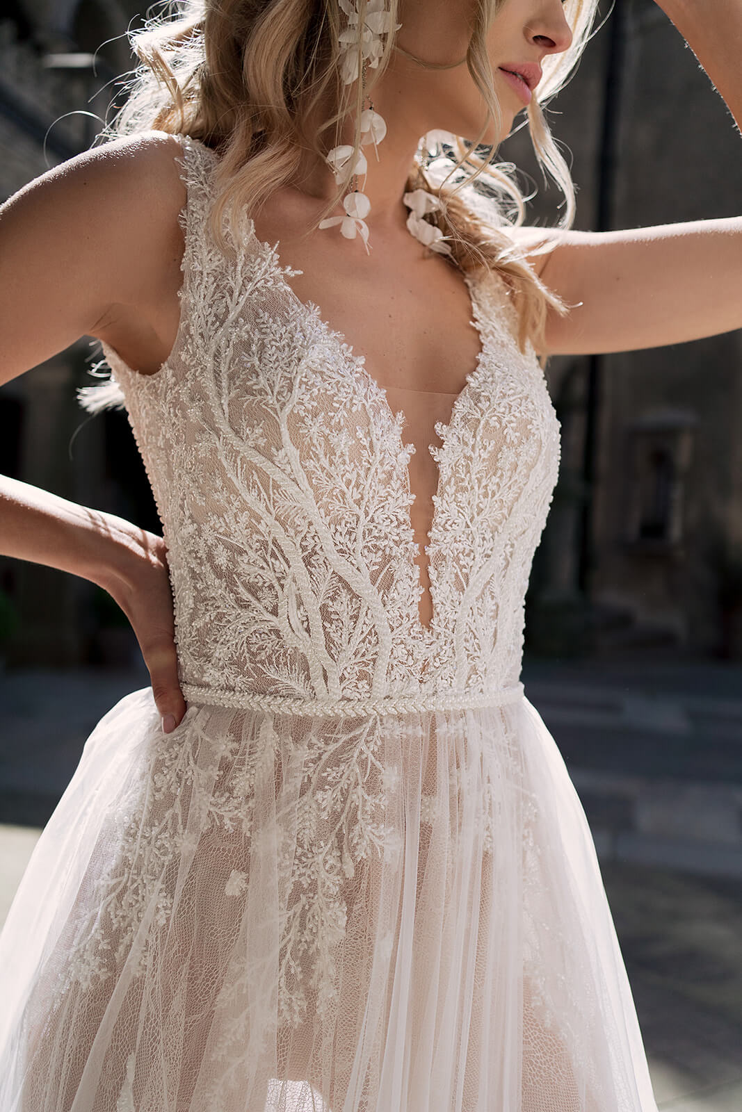 Brautkleid Livia aus der Nähe, Spitzenoberteil und Perlengürtel, erhobene Arme