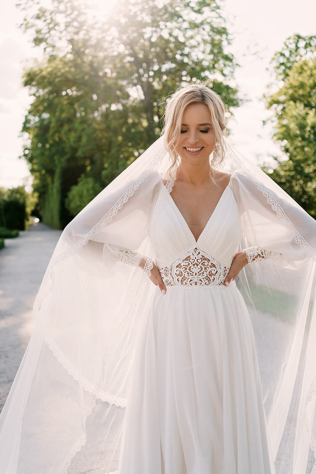 Brautkleid Safona mit Schleier über den Schultern, Halbfigur im Schlossgarten