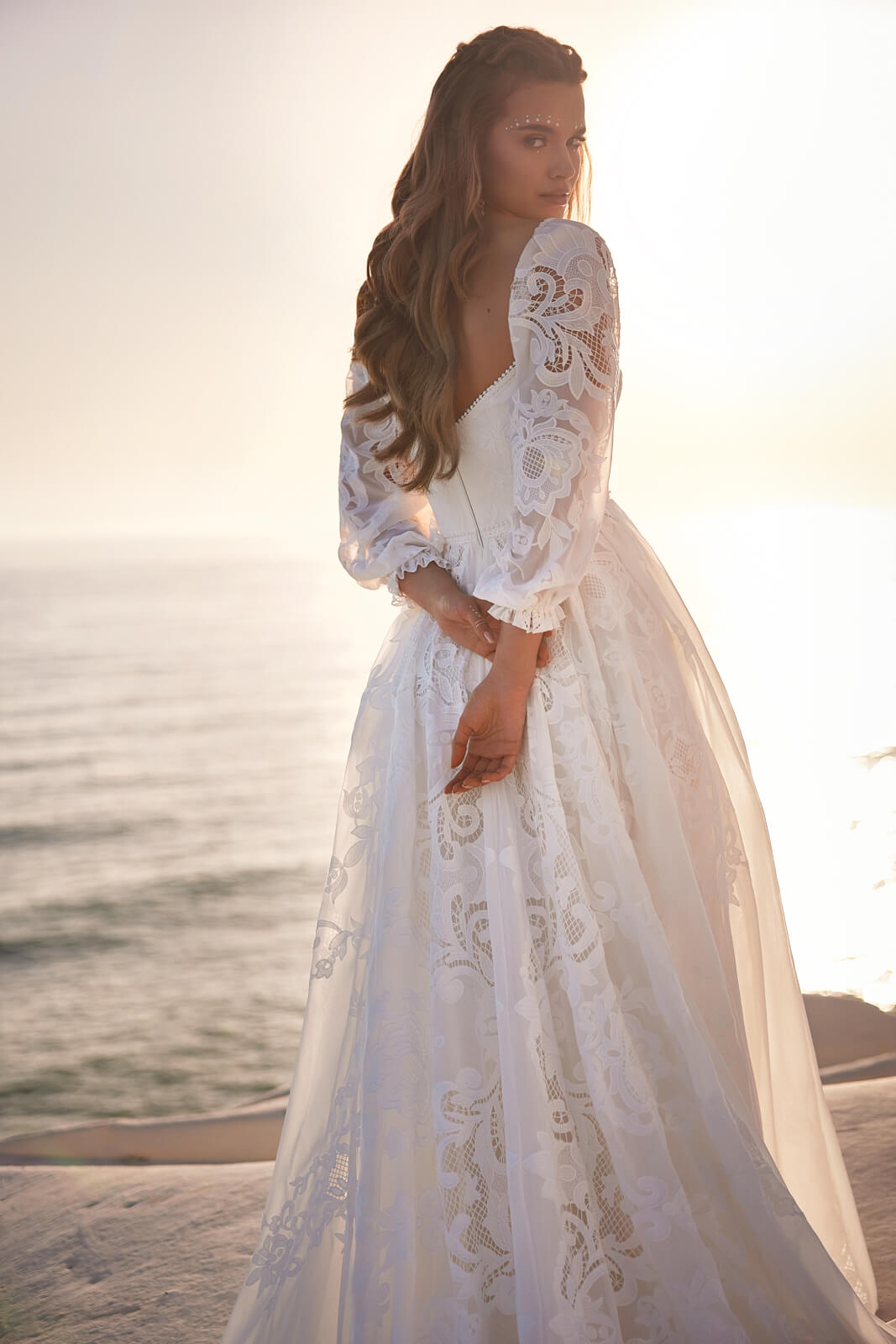 Brautkleid Rania am Meer, Braut über die Schulter, Lochspitze auf den Ballonärmeln