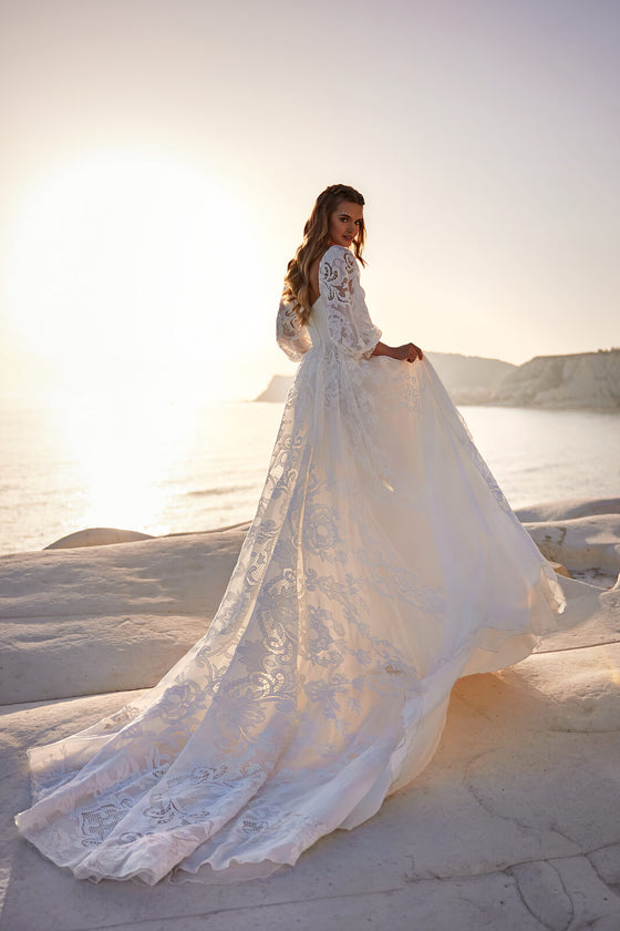 Brautkleid Rania in A-Linie, Schleppe im Gegenlicht, Braut hält den Rock seitlich