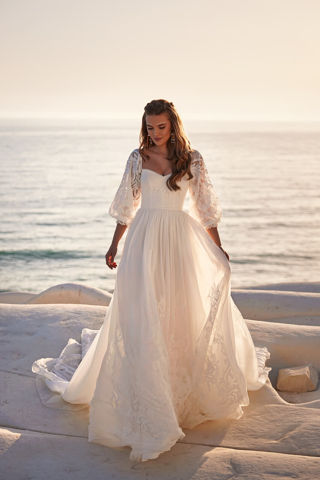 Brautkleid Rania von vorn, fließender Rock mit Spitzenbahnen, ganze Silhouette am Wasser