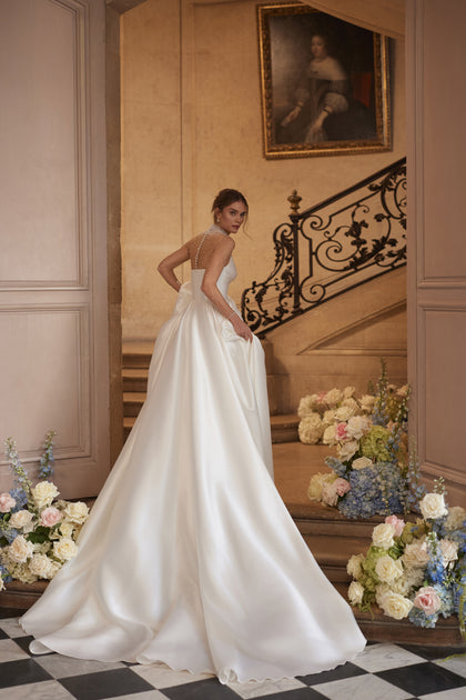 Lucienne wedding dress from the Something Blue 2027 collection – a crystal-embellished illusion neckline and draped satin skirt with a high slit.