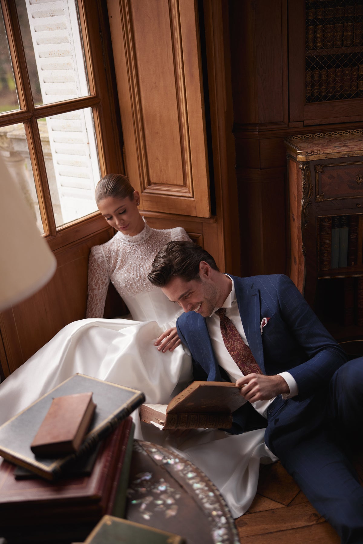 Braut im Kleid Maristella in der Bibliothek, Bräutigam im dunkelblauen Anzug