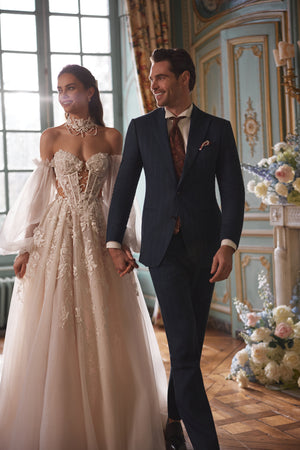 Brautkleid Melusine in A-Linie mit Blütenspitze und Spitzen-Choker, Braut mit Bräutigam im Salon