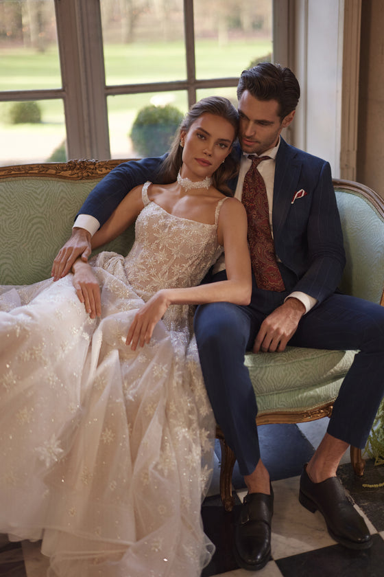 Brautkleid Milkyway auf dem Sofa sitzend neben dem Bräutigam, sternbestickter Tüllrock ausgebreitet