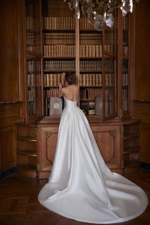 Brautkleid Shella von hinten, Satinrock mit ausgelegter Schleppe am Bücherregal