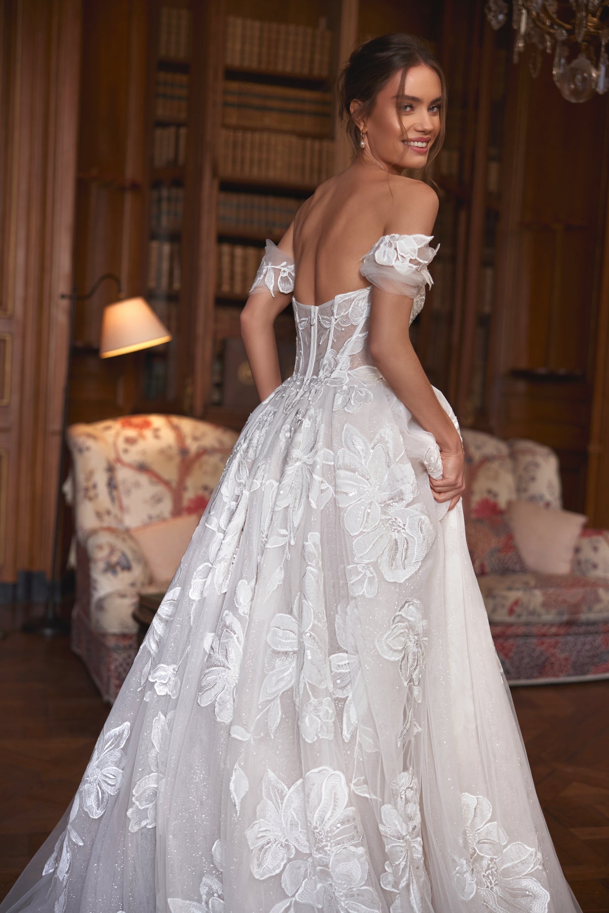 Brautkleid Vespera von der Seite, offener Rücken und Blütenapplikationen auf dem Tüllrock, Halbfigur
