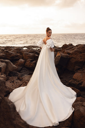 Rückenfreies Brautkleid mit extra langer Schleppe – ideal für Hochzeitsfotos am Meer.