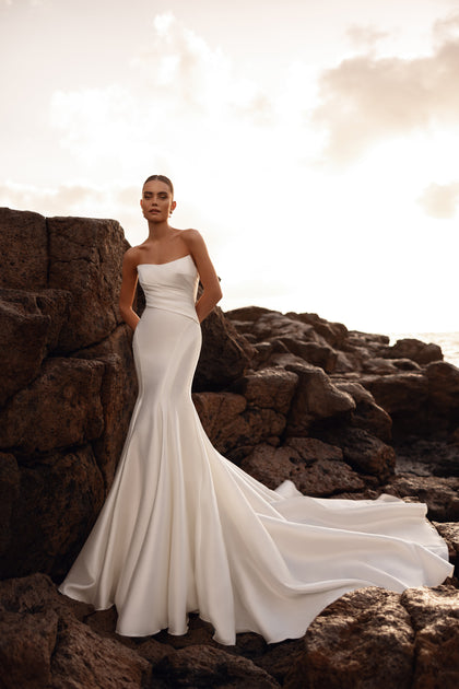 Meerjungfrau-Brautkleid Soraya mit offenem Rücken betont die feminine Figur im goldenen Sonnenuntergang.