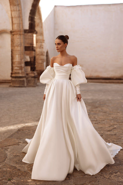 Elegantes Brautkleid Anika mit schulterfreiem Ausschnitt, Puffärmeln und feinen Blumenapplikationen für einen romantischen Look.
