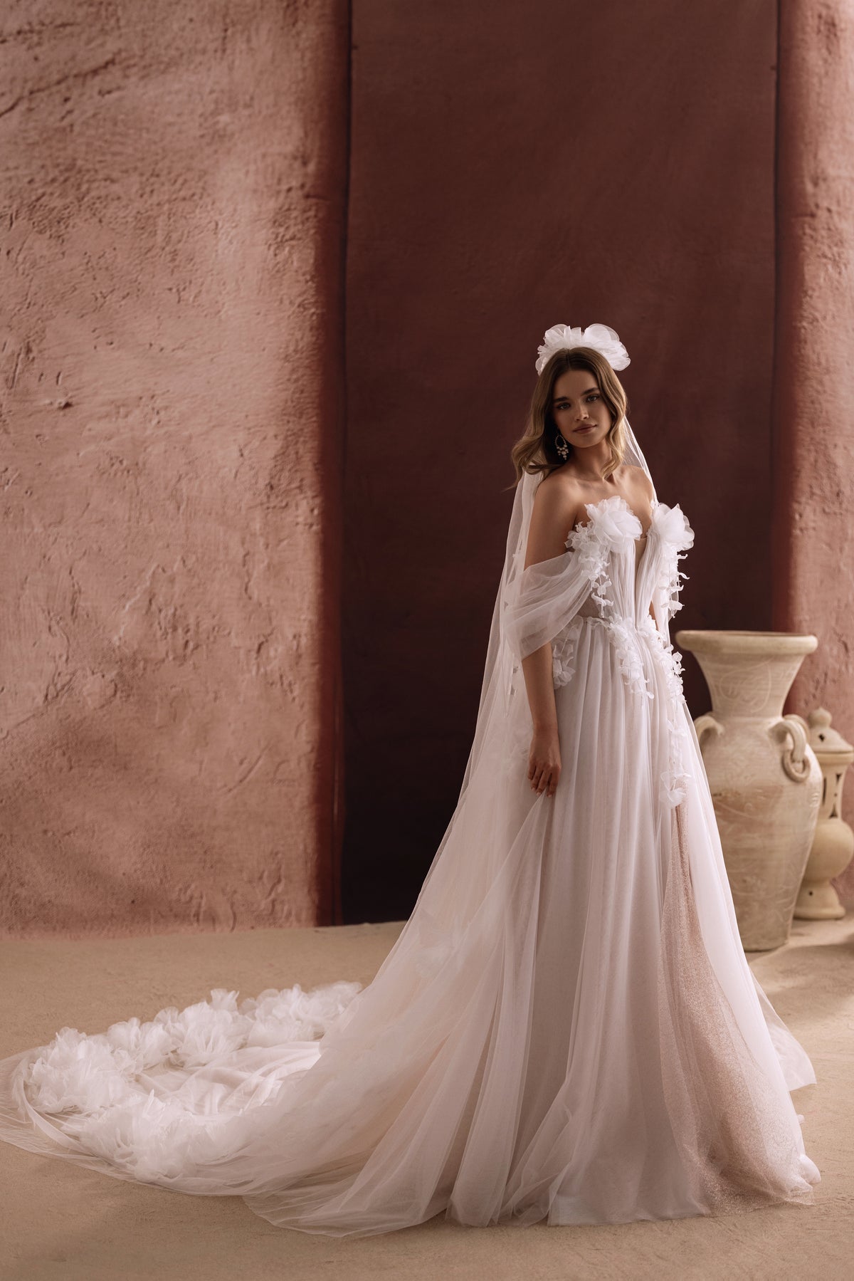 The back of the Bella wedding gown reveals a sweeping tulle train adorned with 3D flowers for a fairytale bridal look.