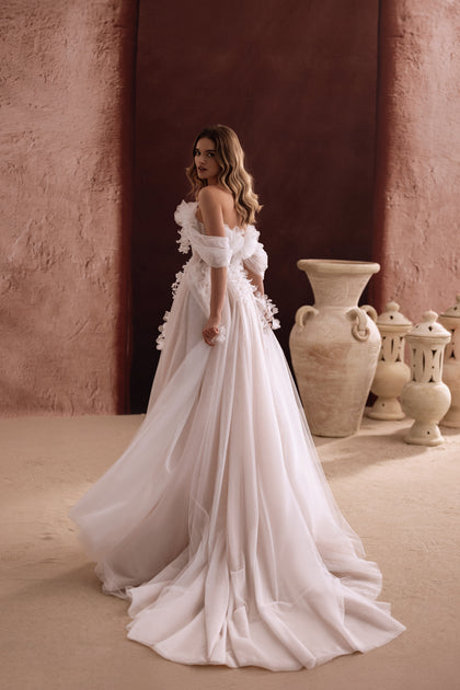 Das Brautkleid Bella mit schulterfreiem Design und langem Tüllschleier verleiht eine märchenhafte Silhouette.