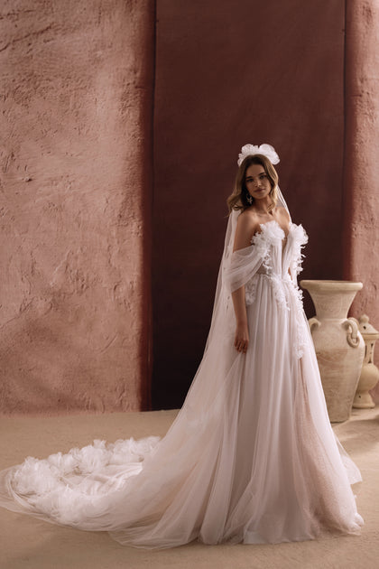 Die Rückansicht des Brautkleids Bella zeigt eine lange Tüllschleppe mit 3D-Blüten für einen märchenhaften Look.