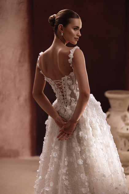 Das Brautkleid Cintra mit transparentem Spitzenoberteil und floralen Verzierungen vereint Leichtigkeit und Eleganz.