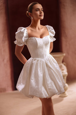 Das kurze Brautkleid Daphne mit Puffärmeln und Korsett-Oberteil vereint romantischen Retro-Stil mit moderner Eleganz.