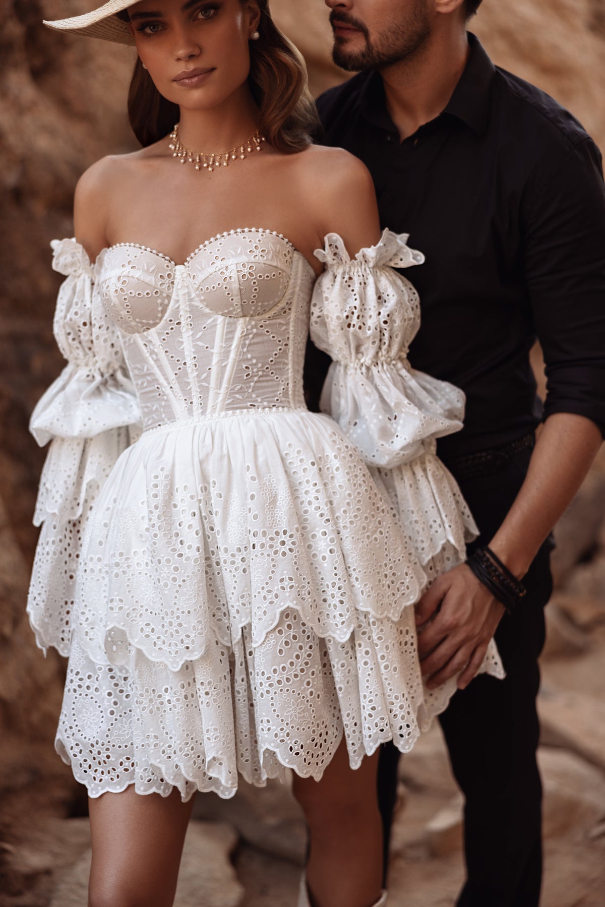 Kurzes Brautkleid Jolene aus Lochspitze, Corsage mit Puffärmeln, Braut mit Hut neben dem Bräutigam