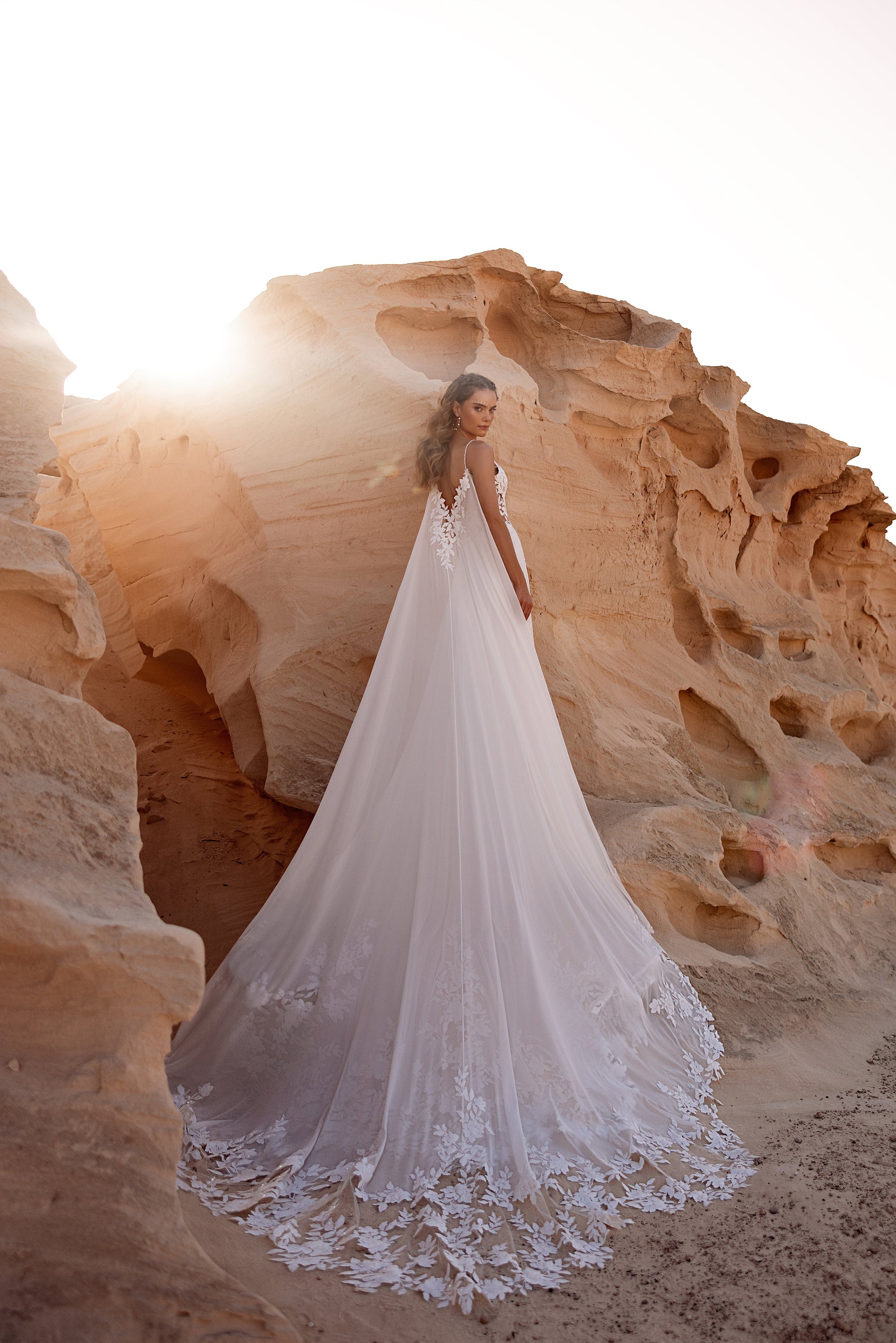 Brautkleid Malika im Gegenlicht, lange Schleppe aus Tüll und Spitze in der Wüste