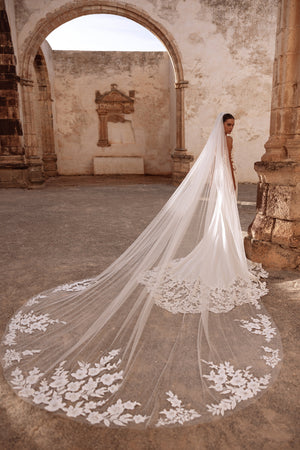 Munira cathedral wedding veil with floral lace appliqués, creating a dramatic bridal look in historic ruins.