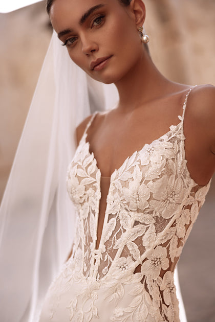 Das Spitzen-Brautkleid Munira mit 3D-Blumenapplikationen und transparenten Einsätzen vereint Moderne und Romantik.