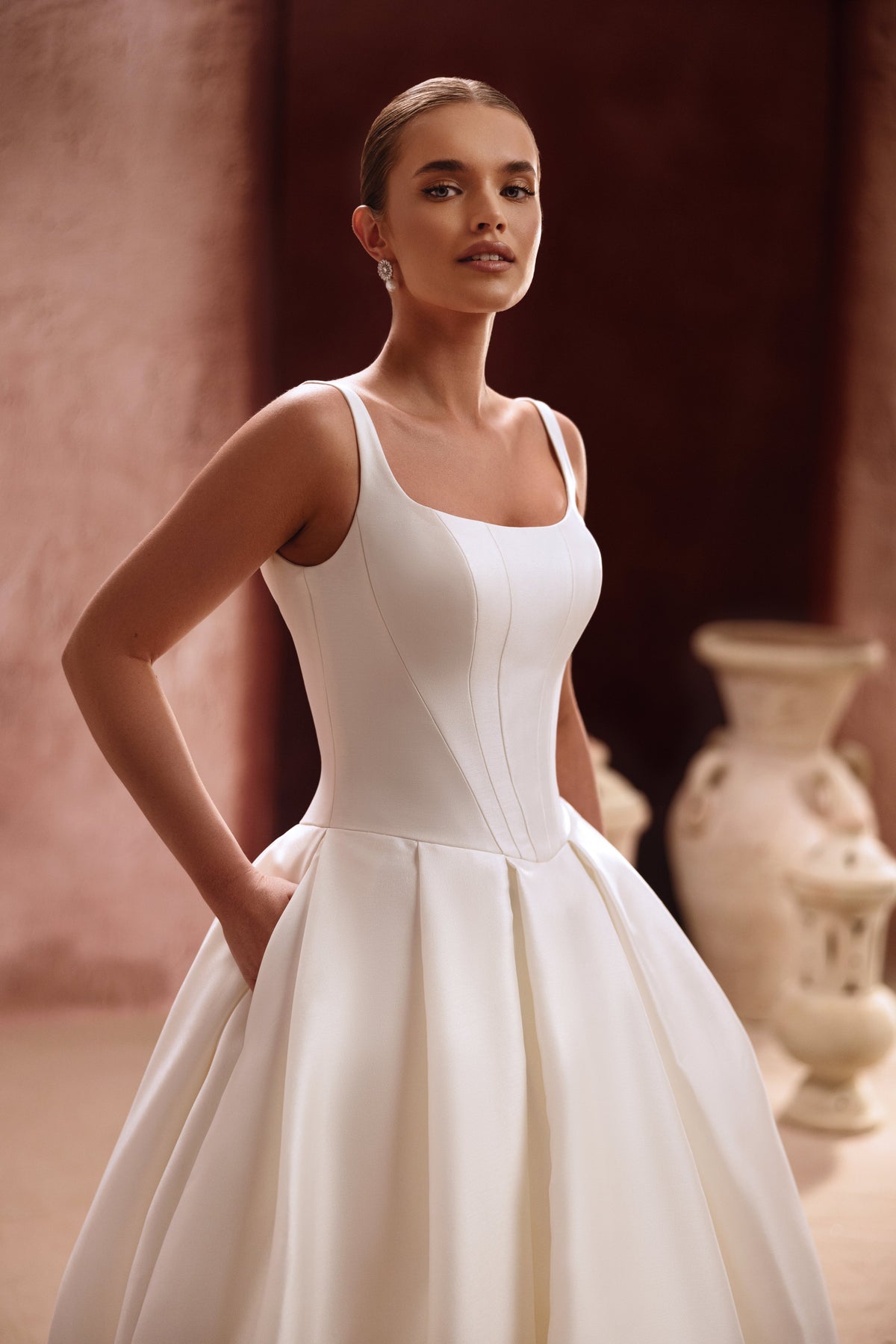 The Nicolette wedding dress features a clean satin bodice with straps and a voluminous princess skirt for a timeless bridal look.