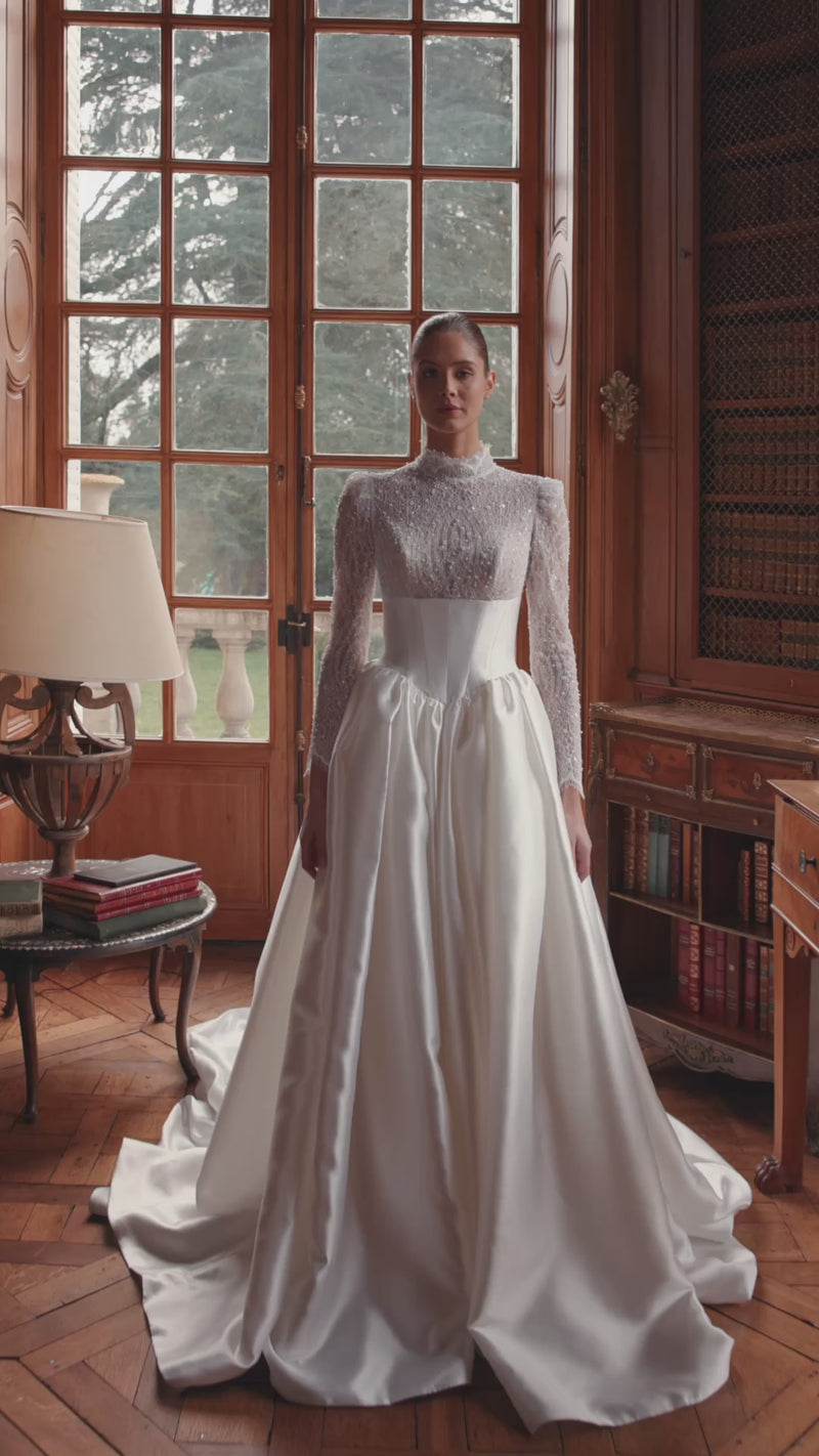 Brautkleid Maristella in Bewegung — A-Linie mit hochgeschlossenem Spitzenoberteil, langen Ärmeln und weitem Satinrock.