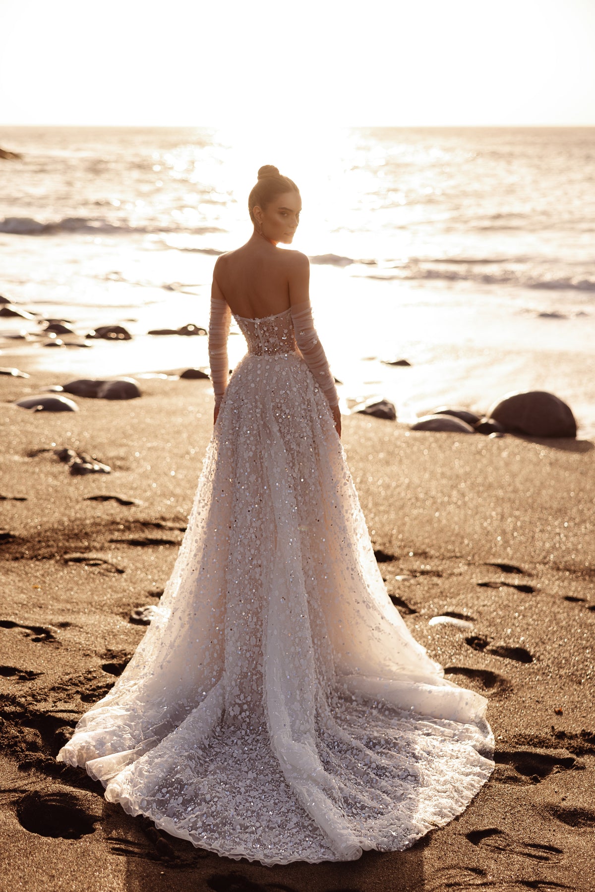 Brautkleid Reem von hinten am Strand, lange Schleppe liegt im Sand