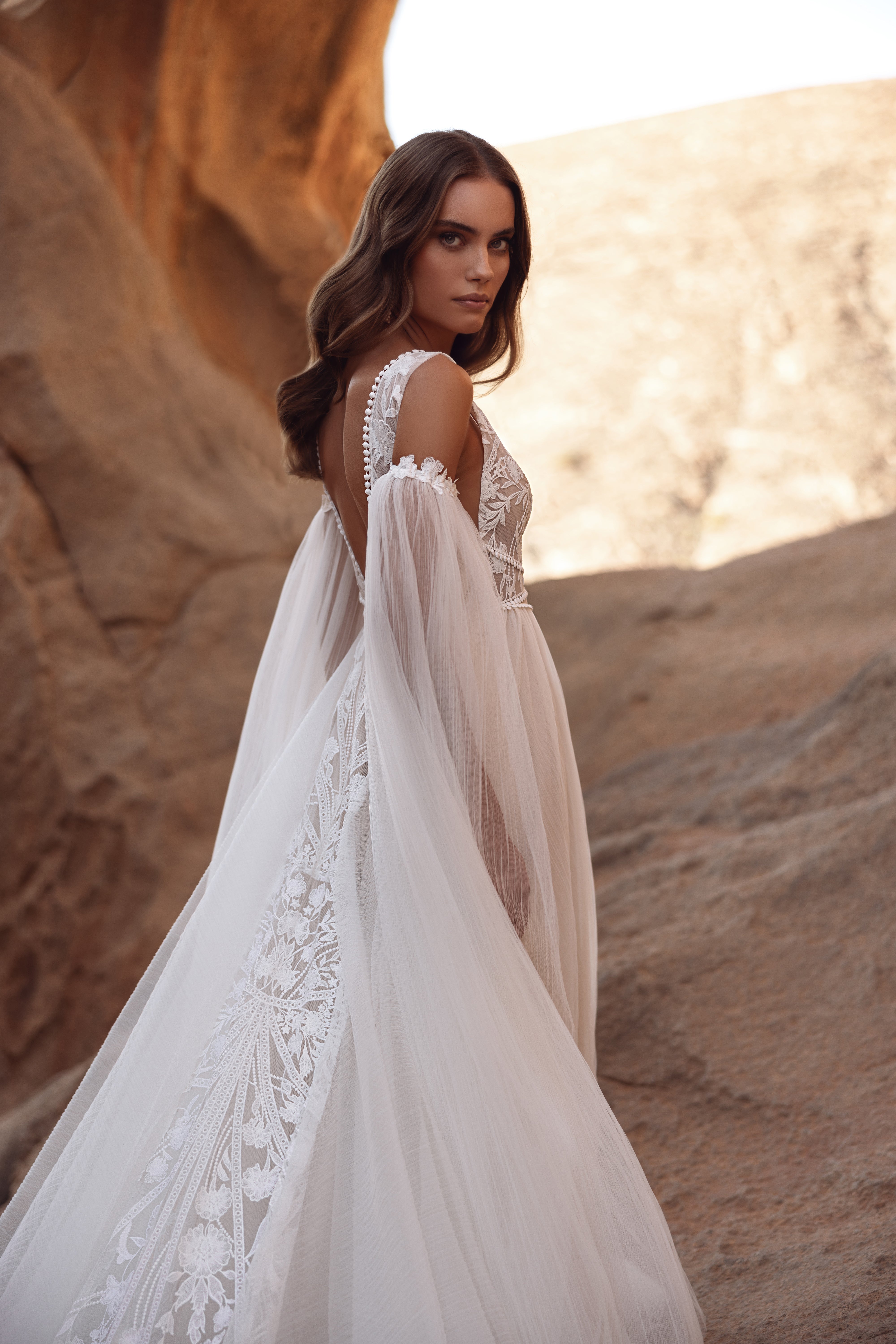 The Salome wedding dress with a deep V-neckline and delicate lace details highlights the feminine silhouette with airy elegance.
