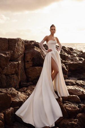 Brautkleid Sarabi in ganzer Länge am Meer, weiter Satinrock mit Beinschlitz