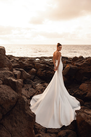 Brautkleid Soraya von hinten am Meer, offener Rückenausschnitt und lange Satinschleppe