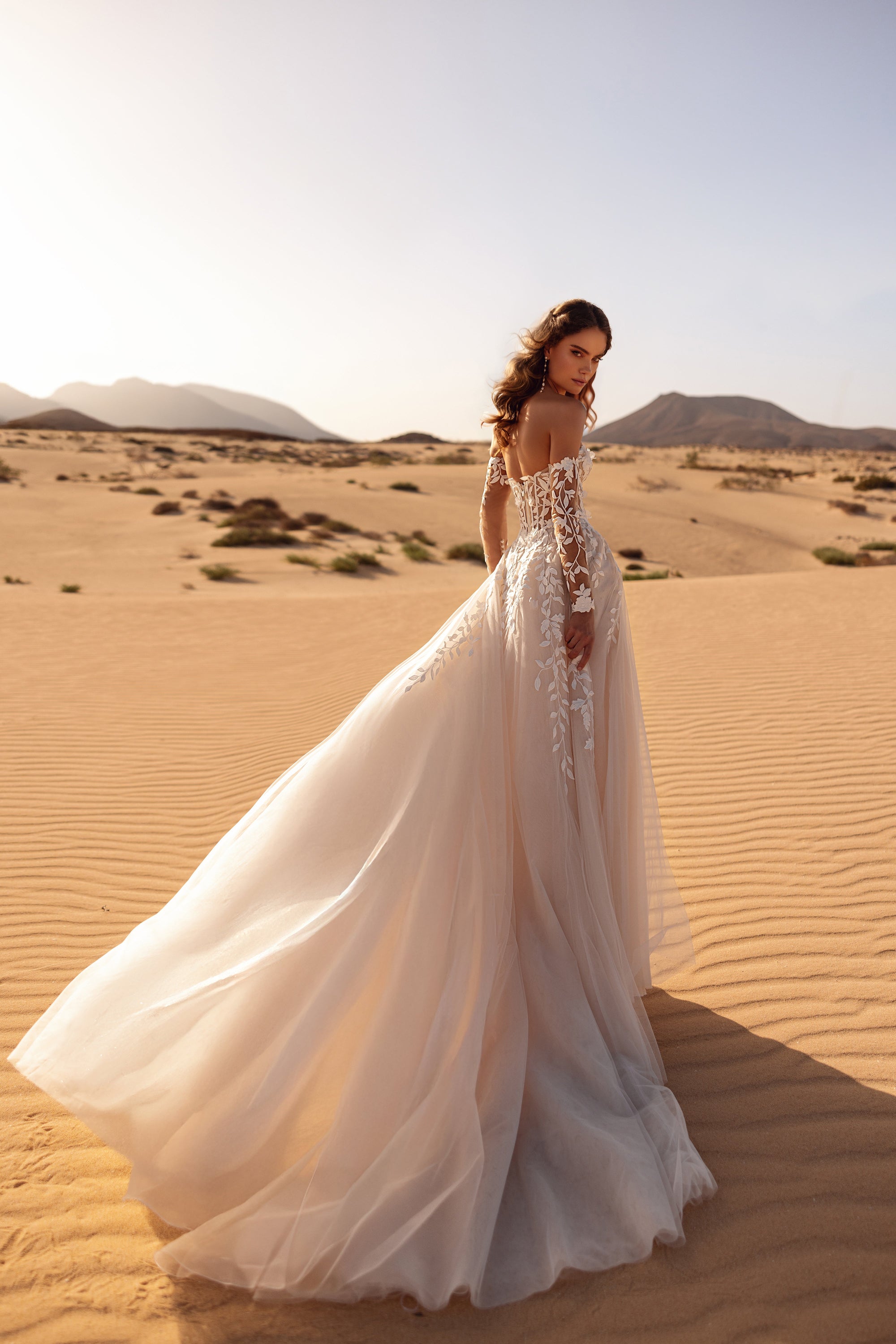 The Tamara wedding dress with off-the-shoulder lace sleeves highlights the bride’s elegance and romantic allure.