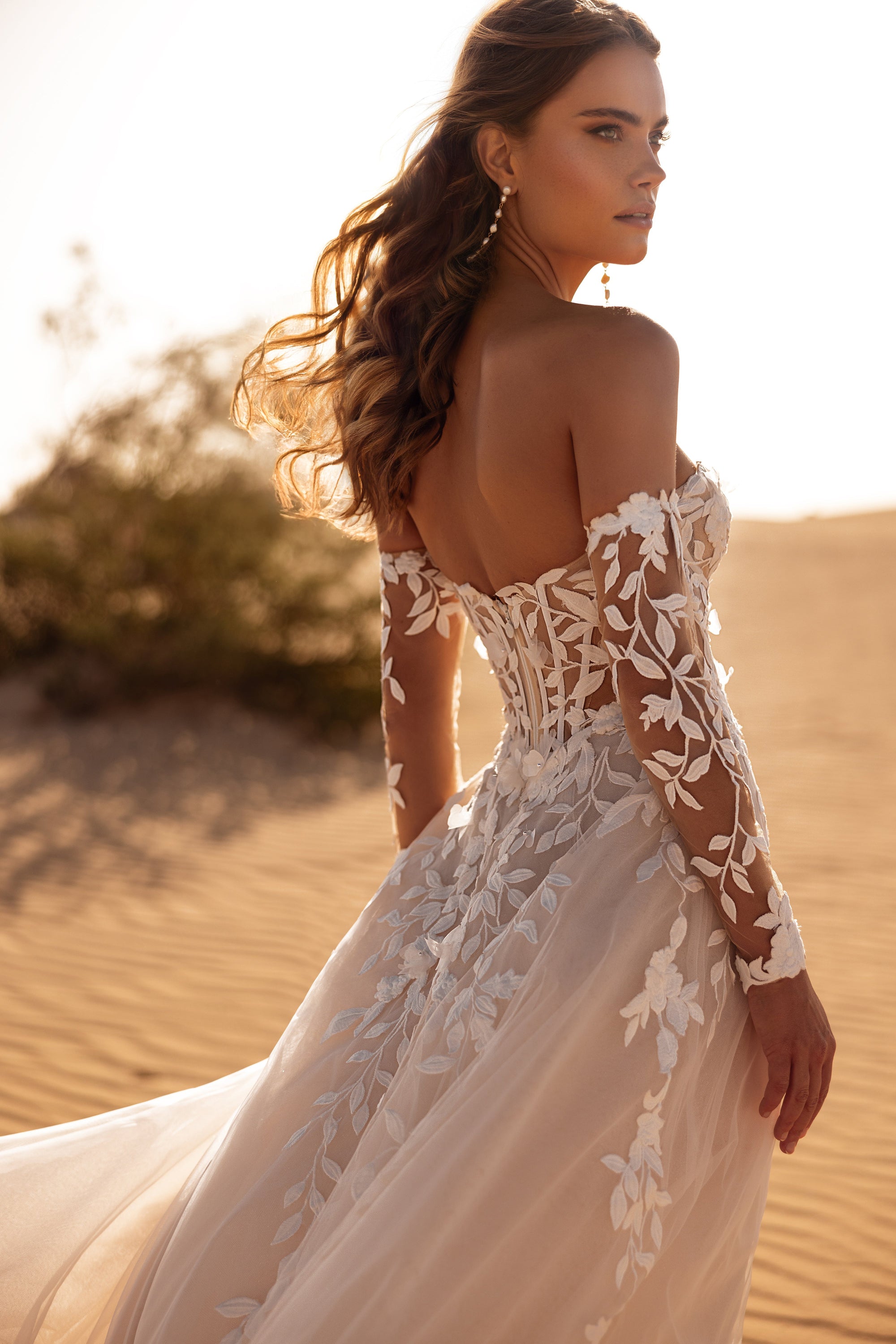 The Tamara wedding gown with off-the-shoulder sleeves and floral lace appliqués creates a sensual and feminine bridal look.